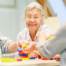 Three seniors sit together at a table participating in a colorful block-building activity.
