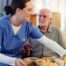 Caregiver providing senior care at home to manage parkinson’s and related symptoms.